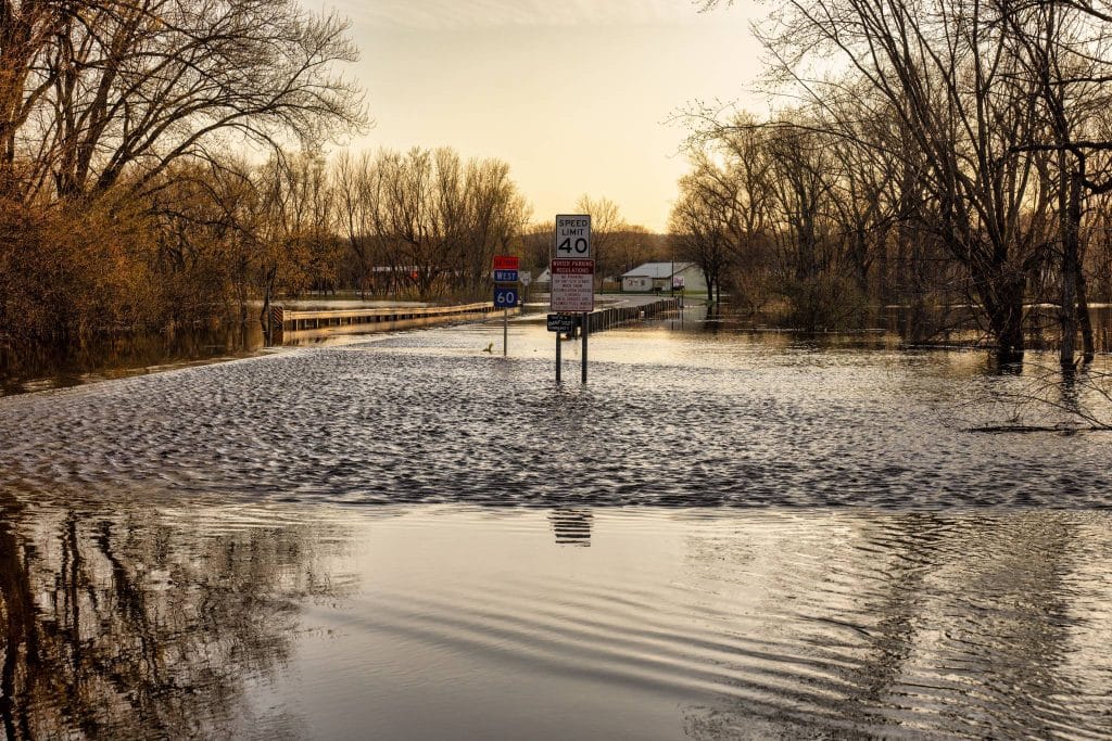 Road Flooded, Street signs are half in the water, sun is setting